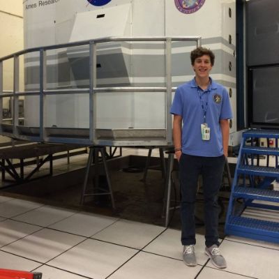 Cooper Matheson is standing Infront of a huge machine posing for the photo.